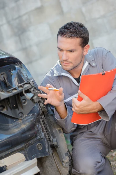 Mechanik dokonywanie oceny uszkodzony samochód — Zdjęcie stockowe