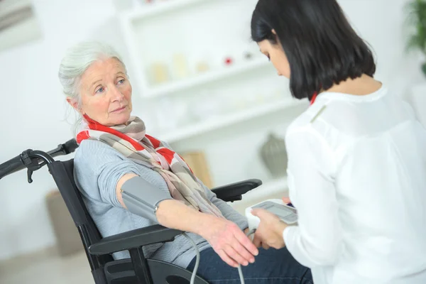 Alte Dame im Rollstuhl lässt sich Blutdruck abnehmen — Stockfoto