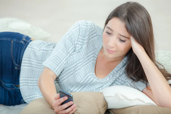 Envoi d'un message texte pendant que vous êtes allongé sur un canapé — Photo