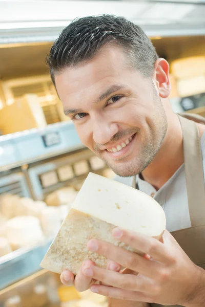 Assistente de loja segurando pedaço de queijo — Fotografia de Stock