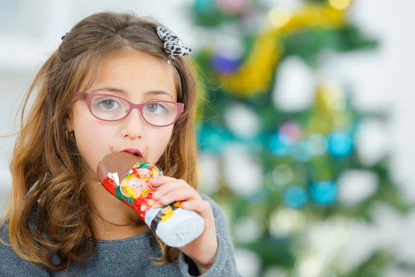 Little girl eating chocolate at Christmas — Stock Photo, Image