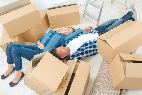 Exhausted couple laying amongst cardboard boxes — Stock Photo, Image