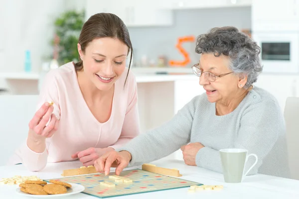 Mulher idosa jogando um jogo de tabuleiro — Fotografia de Stock