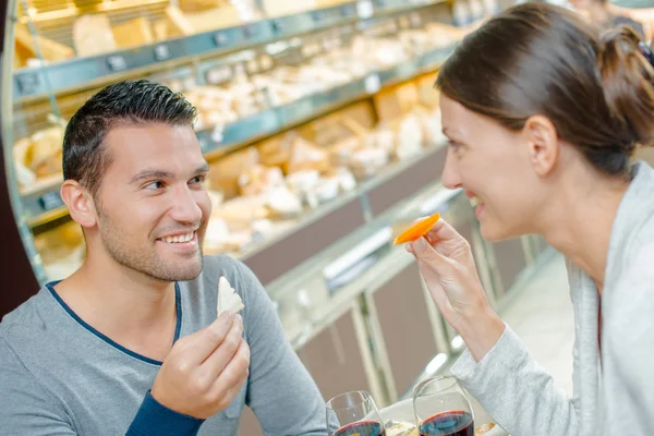 Couple eating meal, holding cheeses — Stock Photo, Image