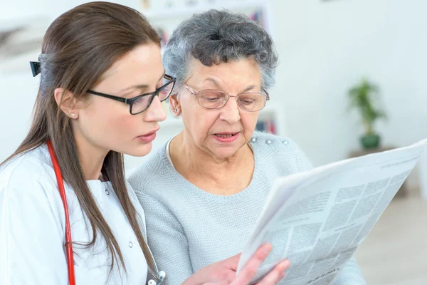 Lendo jornal com uma senhora idosa — Fotografia de Stock