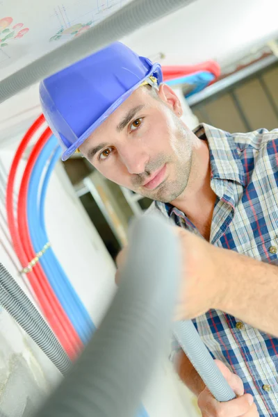 Elektriker som arbetar genom en öppen taklucka — Stockfoto