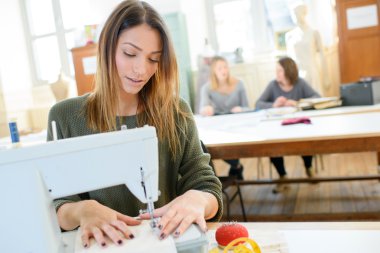 Woman using a sewing machine in class clipart