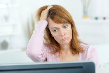 Stressed woman looking at her computer screen clipart