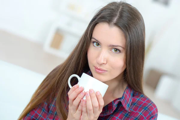 Kvinnan dricka en kopp kaffe i soffan — Stockfoto