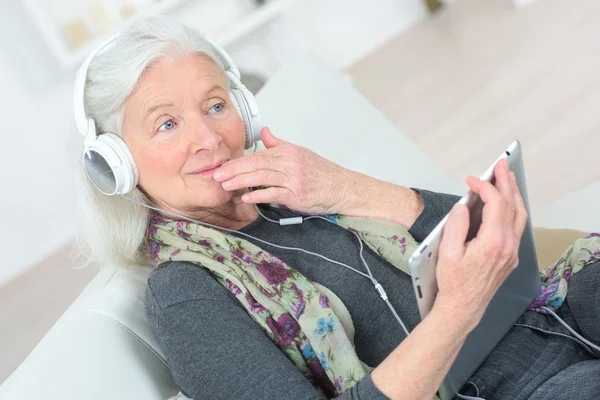 Senior senhora ouvindo música através de fones de ouvido — Fotografia de Stock