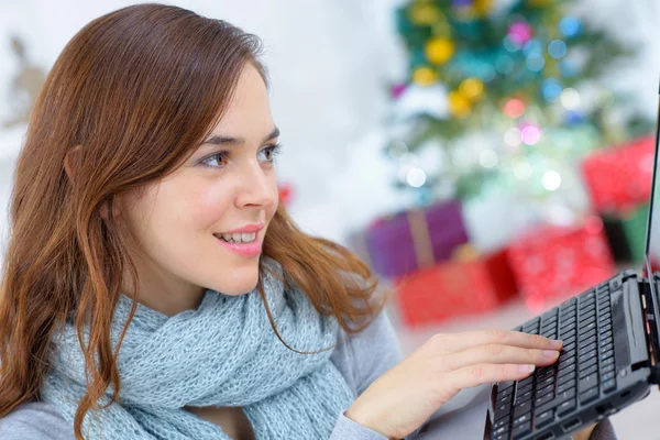 Vrouw met behulp van een laptop door haar kerstboom — Stockfoto