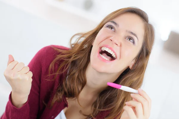 Happy woman holding a pregnancy test — Stock Photo, Image