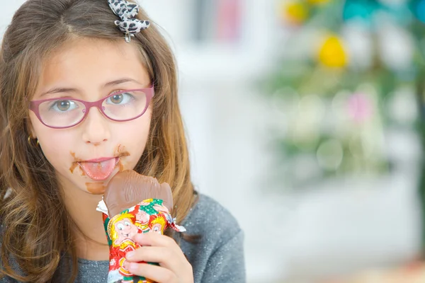 Liten flicka äter choklad vid jul — Stockfoto