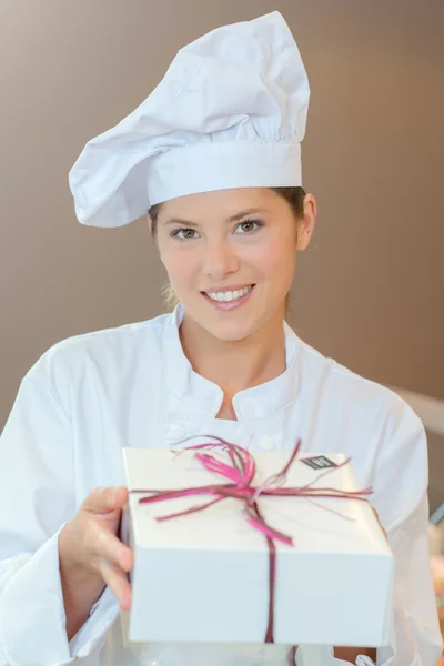 Konditormeister hält eine Geschenkbox in der Hand — Stockfoto