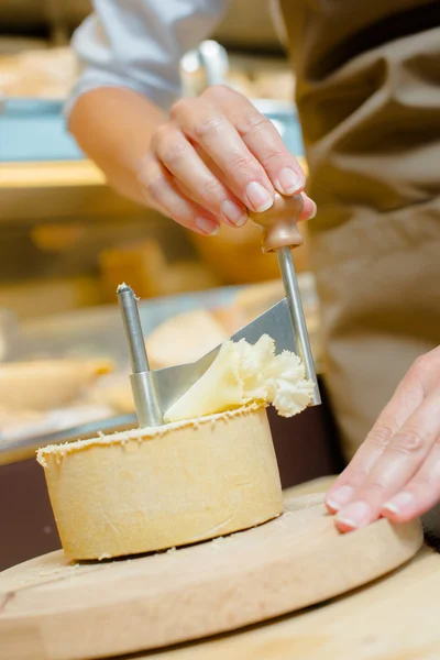 Shaving a layer off of a cheese — Stock Photo, Image