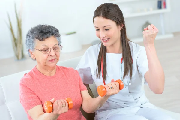 Helping senior woman work out — Stock Photo, Image