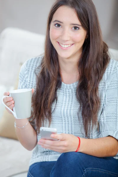 Teen holding cup and mobile — Stock Photo, Image