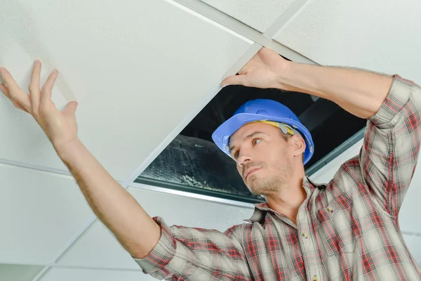 Peering under a ceiling panel — Stock Photo, Image