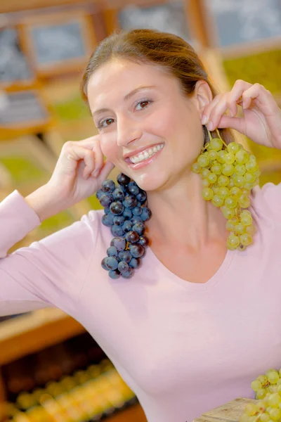 Mulher engraçada segurando uvas como brincos — Fotografia de Stock