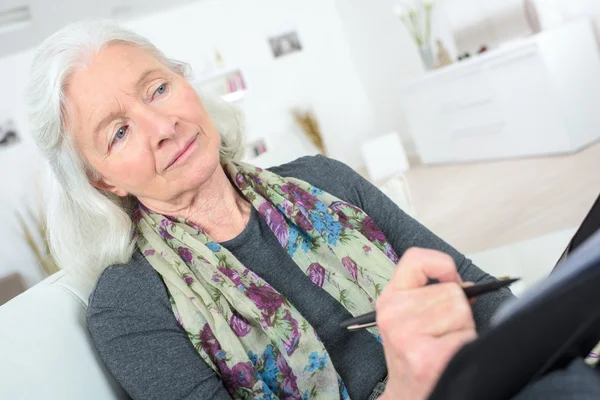 Fundersam senior med ett anteckningsblock — Stockfoto