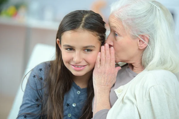 Kleines Mädchen und Oma flüstern Geheimnisse — Stockfoto