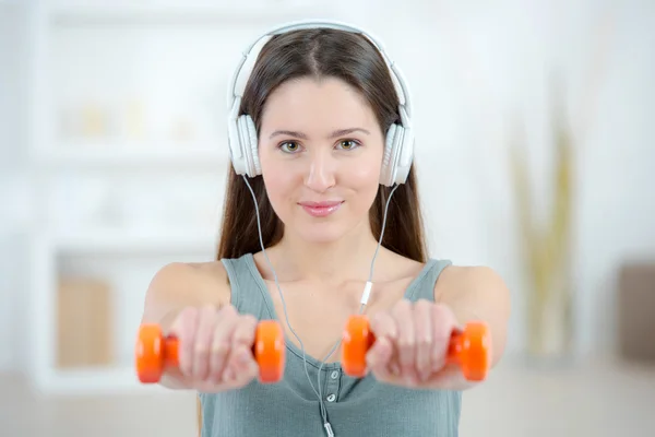 Senhora com fones de ouvido e halteres — Fotografia de Stock