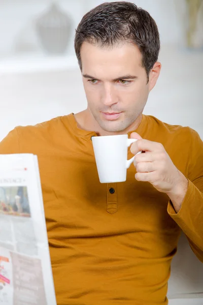 Человек, пьющий кофе во время чтения газеты — стоковое фото