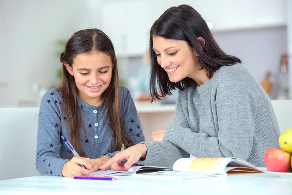 Mamá ayudando a su hija a hacer su tarea — Foto de Stock