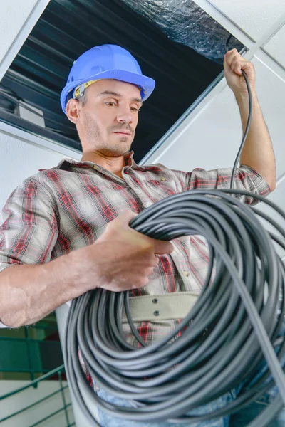 Eletricista que trabalha em um teto — Fotografia de Stock