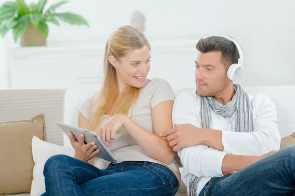 Couple relaxant sur le canapé avec des gadgets — Photo