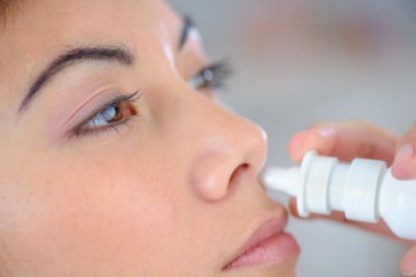 Woman using a nasal spray clipart