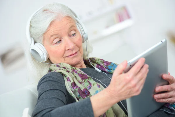 Dame âgée écoutant de la musique à travers des écouteurs — Photo