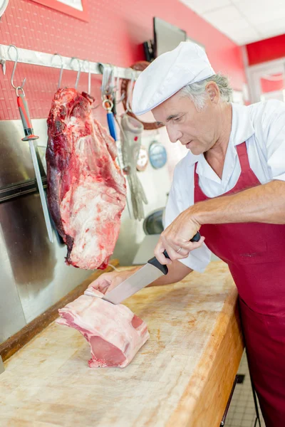 Butcher cutting chops and apron — Stock Photo, Image