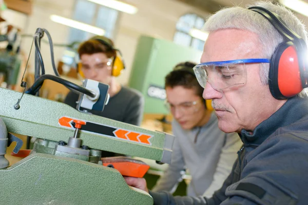 Erfahrener Tischler unterrichtet zwei Teenager — Stockfoto