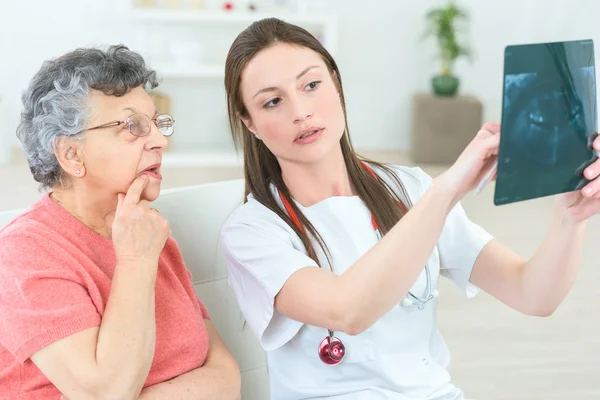 Zeigt einer älteren Patientin ihr Röntgenbild — Stockfoto