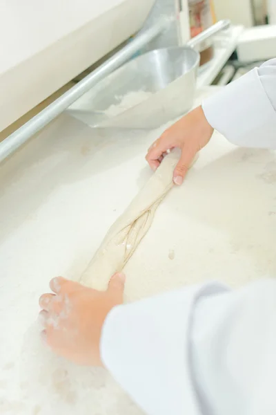 Hands rolling dough and baguette — Stock Photo, Image