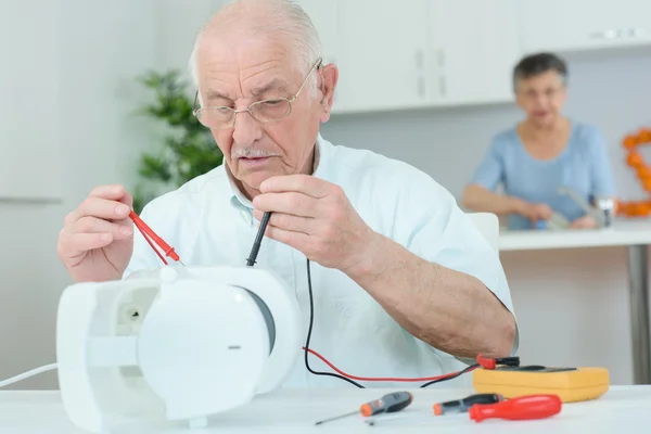 Uomo anziano che utilizza multimetro su apparecchio elettrico — Foto Stock