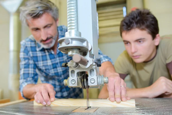 Charpentier enseignant apprenti à utiliser une scie à banc — Photo