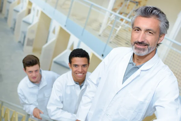 Man with two young men in white jackets — Stock Photo, Image