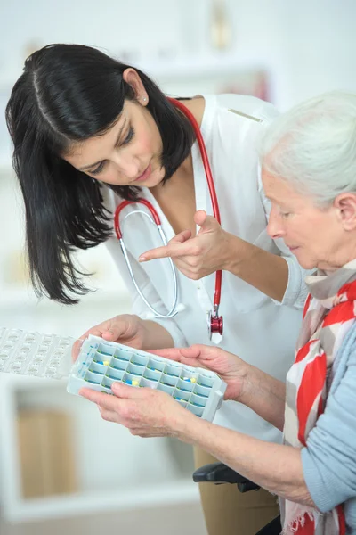 Infermiera aiutare una vecchia donna con la sua scatola pillola — Foto Stock