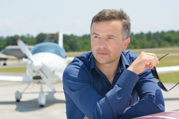 Retrato del hombre en el aeropuerto sosteniendo gafas de sol — Foto de Stock