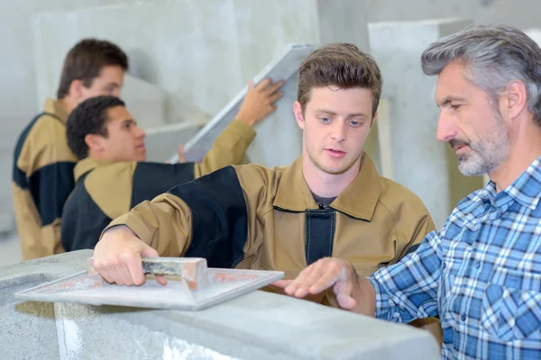 Profesor mostrando aprendiz cómo flotar cemento —  Fotos de Stock