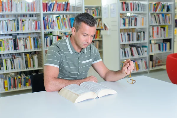 Homem lendo na biblioteca — Fotografia de Stock