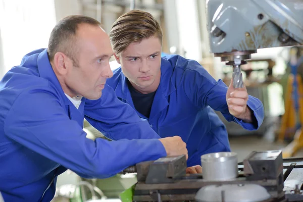 Twee werknemers kijken naar boor op industriële machine — Stockfoto