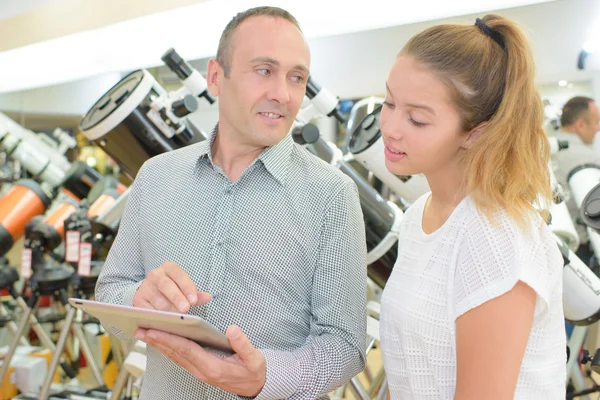 Mann und Frau schauen in Teleskopladen auf Tablet — Stockfoto