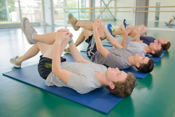 Quatre hommes au sol faisant de l'exercice, jambes courbées — Photo