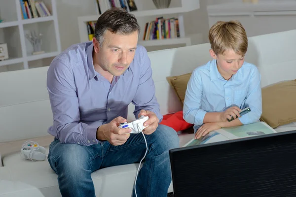 Adult playing computer game, child photographing book — Stock Photo, Image