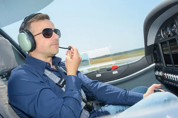 Homem na cabine de pilotagem de aeronaves usando fones de ouvido com microfone — Fotografia de Stock