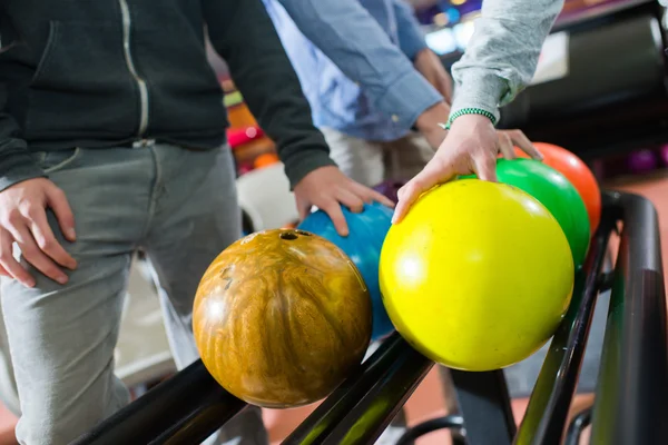 Drei Männer wählen ihre Bowlingkugeln — Stockfoto