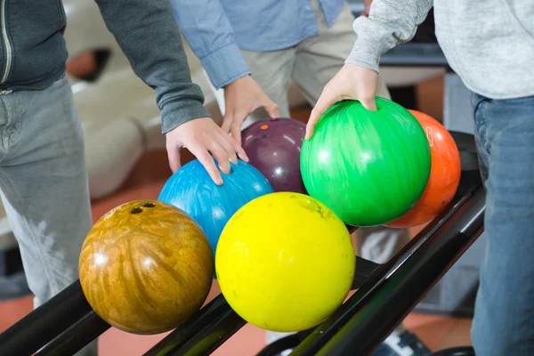 Drei Männer suchen Bowlingbälle aus — Stockfoto